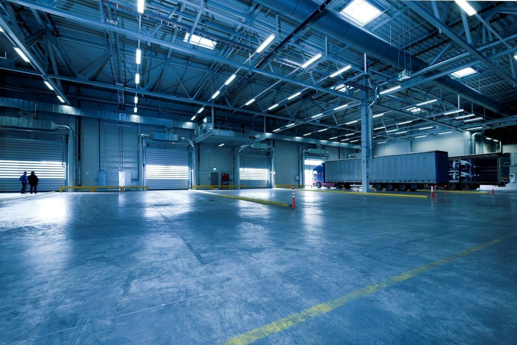 Wide view of an empty modern warehouse with industrial lighting and trucks.